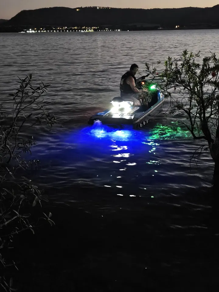 Jet ski navegando à noite com brilho azul e verde
